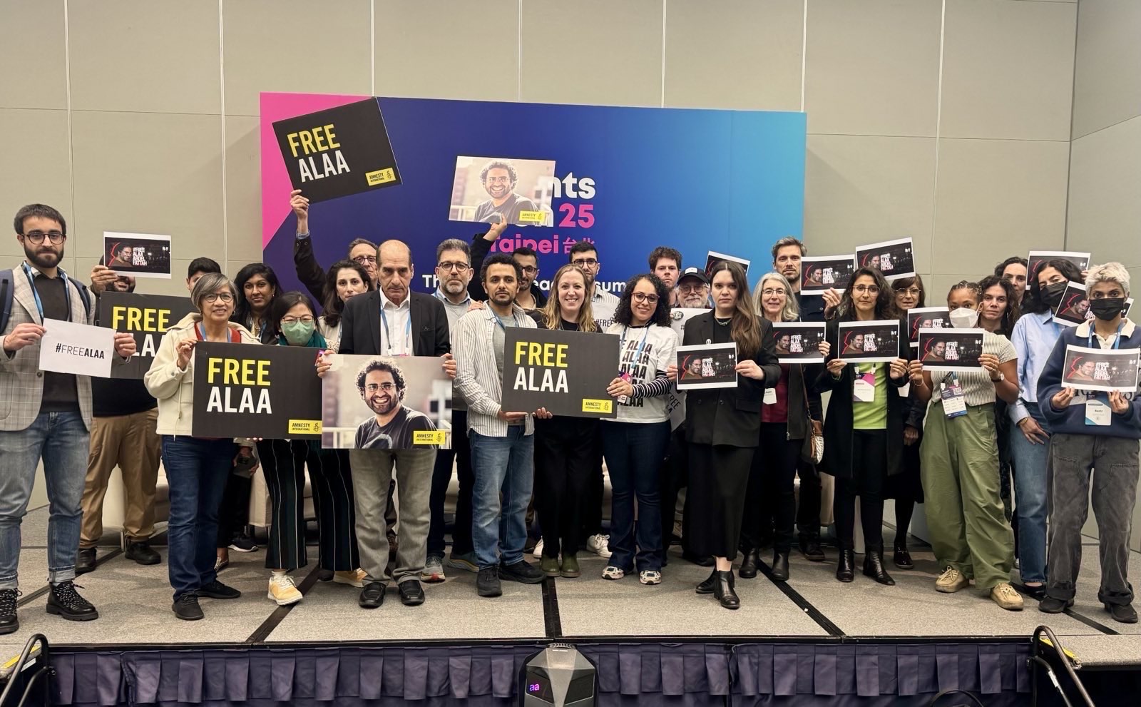 a group of people at RightsCon in Taipei holding signs for Alaa Abd El Fattah to be freed a group of people at RightsCon in Taipei holding signs for Alaa Abd El Fattah to be freed